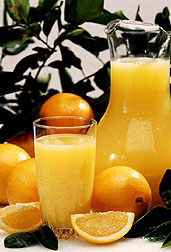 Photo: A pitcher and glass of orange juice is set among fresh oranges. Link to photo information