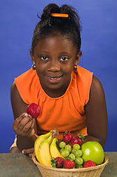 Girl about to eat a strawberry that she picked from a bowl of fresh fruit. Link to photo information