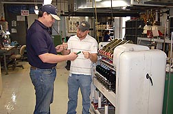 Materials engineer Chris Delhom (left) and technician E.J. Deshotel examine miniature spinning equipment.