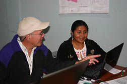 Jorge Delgado and Rosa Juana Arévalo sitting in front of computer screens.