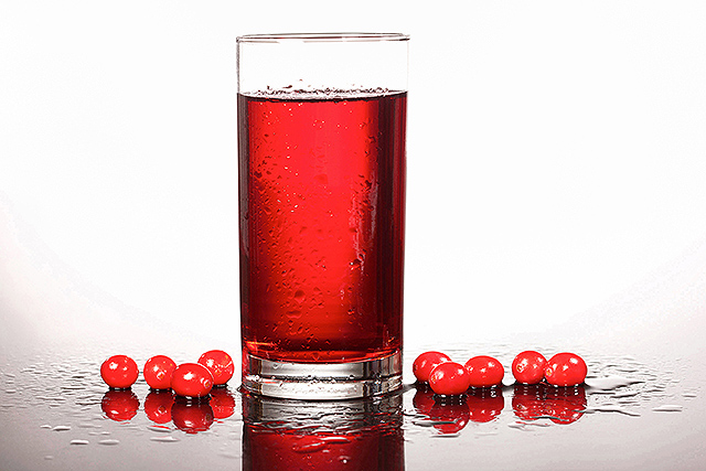 A glass of cranberry juice and fresh cranberries.