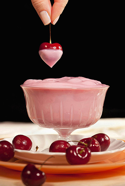 heart shaped cherry dipped in a dish of yogurt