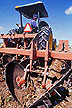 Field technician driving tractor-drawn stalk puller