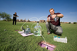 Scientist drawing a water sample from a large lysimeter while another scientist collects soil samples