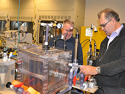 Two researchers inspect a prototype bioreactor used to treat wastewater in space. 