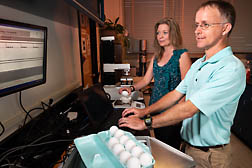 scientists in test kitchen weighing eggs
