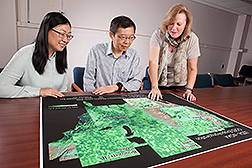 Three scientists looking at maps showing crop water use in U.S. agricultural landscapes