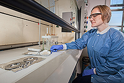 A chemist preparing sampling materials for analysis in a lab hood