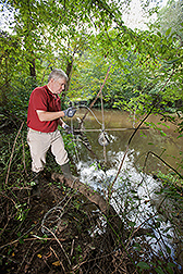 A scientist placing sampling equipment into a stream