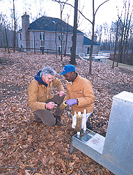 Photo: Entomologist John Carroll (left) and Kenneth Young examining four-poster deer feeder in Maryland
