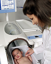 Woman in lab coat looks at infant in Pea Pod chamber tray.