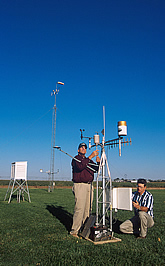 Researchers check and adjust the equipment at a field weather station. Link to photo information
