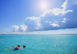 Two people snorkeling under bright sunlight.