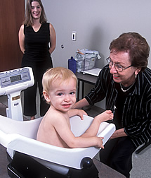 A nutritionist weighs a baby as the mother looks on: Link to photo information