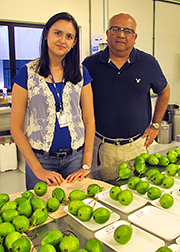 Atanu Biswas and Roselayne Furtado standing in front of a table full of apples. 